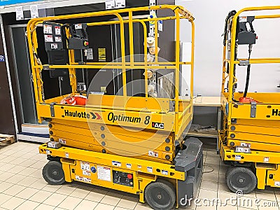 Mobile hydraulic lift for lifting people and cargo on racks in a supermarket at the warehouse. Belarus, Minsk, October 5, 2018 Editorial Stock Photo