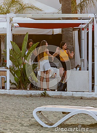 Three girls are dancing at a beach bistro at MCKenzie beach in L Editorial Stock Photo