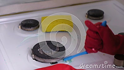 Las manos de la mujer en estufa de gas sucia de los lavados de goma rojos de los guantes con un cepillo y una esponja almacen de metraje de vídeo Las manos de la mujer en estufa de gas sucia de los lavados de goma rojos de los guantes con un cepillo y una esponja almacen de metraje de vídeo