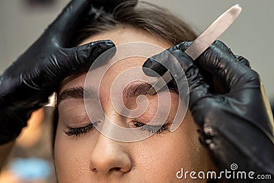 lashmaker makes a beautiful eyebrow contour with tweezers. female face close-up. Stock Photo