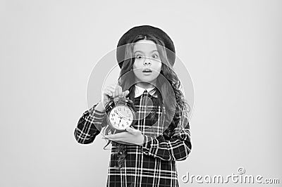 Last chance deadline. Anxious child worried about deadline on yellow background. Stressed little girl holding clock Stock Photo