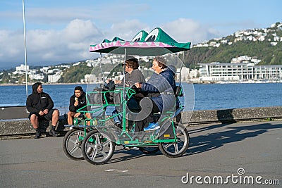 Late afternoon long shadows and people passing on old wharf promenade on city waterfront Editorial Stock Photo