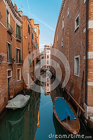 Lateral canal with docked boats in Venice, Italy. Reflections and ble sky Stock Photo