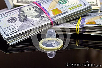 Latex condom with dollar packs on black background. Sex, love for money and prostitution concept Stock Photo