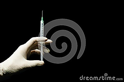 Latex gloved hand holding syringe against a black background Stock Photo