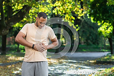 Latin american runner sportsman has severe stomach pain, man holding hand on side of stomach after doing exercise and Stock Photo