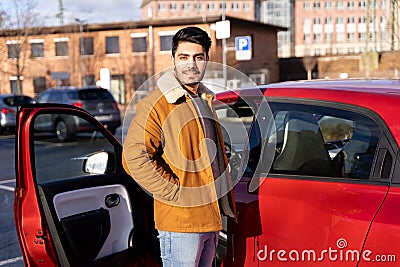 Latin or arab man standing near car with opened door on parking slot of city Stock Photo