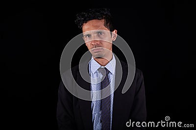 Latin business man with sad face, isolated on black background. Young adult frustrated young man doing bad business. Stock Photo