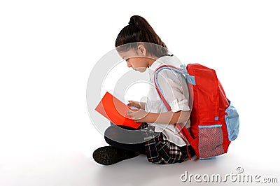 Latin child reading textbook or notepad smiling sitting on the floor Stock Photo