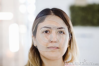 Latin Cosmetologist preparing to mexican woman for eyebrow permanent makeup procedure in Mexico, Microblading closeup Stock Photo