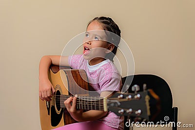 Latin girl playing electroacoustic guitar next to the amplifier Stock Photo