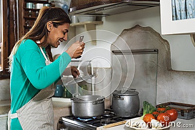 Latin mature woman cooking in old vintage kitchen - Smiling mother preparing lunch Stock Photo