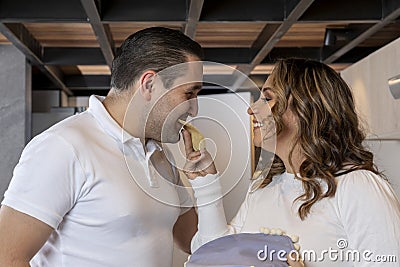 Latin woman feeding her husband tortilla in the mouth while preparing breakfast Stock Photo