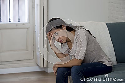 Latin woman lying at home sitting on couch crying worried suffering depression feeling sad Stock Photo