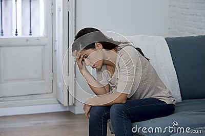 Latin woman lying at home sitting on couch crying worried suffering depression feeling sad Stock Photo