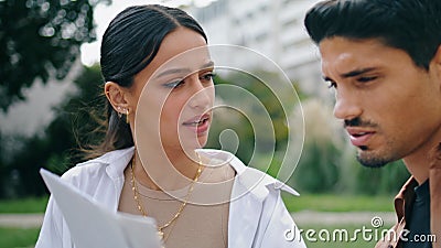 Latina couple reading documents outdoors closeup. Serious coworkers working park Stock Photo