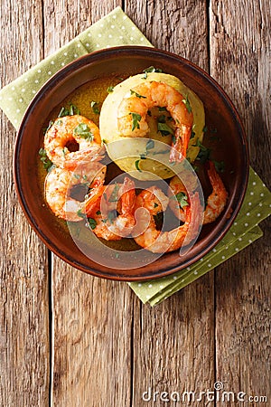 Latino american main course mofongo with shrimps and broth close-up on a plate. Vertical top view Stock Photo