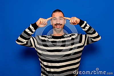 Latino man with beard wearing striped sweater smiling pointing to the head with the finger of both hands, great idea or Stock Photo