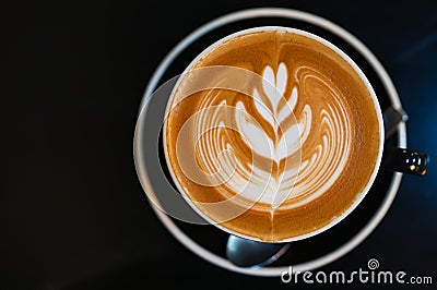 Latte art coffee in black cup on black table Stock Photo