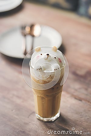 Latte art. A glass of iced coffee with 3d latte art of happy teddy bear smiling. Vintage filter applied Stock Photo