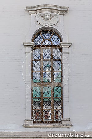 Lattices on a narrow long window in the white wall of the temple. Exterior. Vertical Stock Photo
