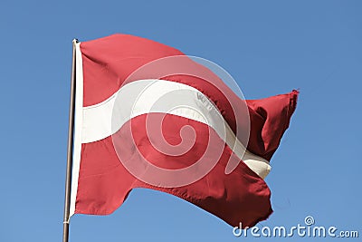 Latvian flag flying on flagpole Stock Photo