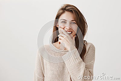 Laugh increases life span. Studio shot of positive young woman with brown hair chuckling and covering mouth with hand Stock Photo
