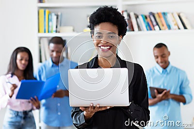 Laughing african american businesswoman at computer with group of black business people Stock Photo