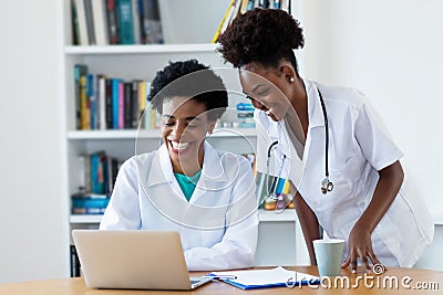 Laughing african american female doctor with young nurse Stock Photo