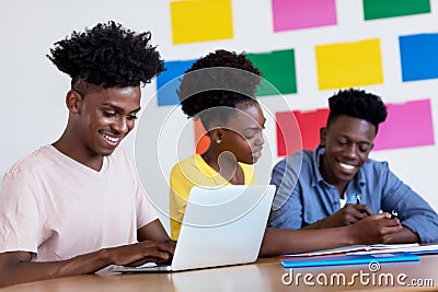 Laughing african american male student at computer with group of students Stock Photo