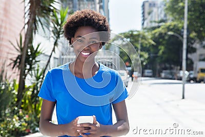 Laughing african american woman in a blue shirt typing message Stock Photo