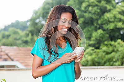 Laughing african american woman with long hair messaging with mo Stock Photo