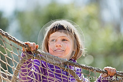 Laughing baby girl climbing on ropes Stock Photo