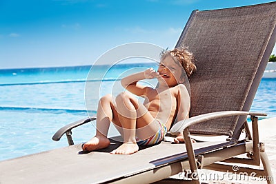 Laughing boy laying on sun lounger and sunbathing Stock Photo