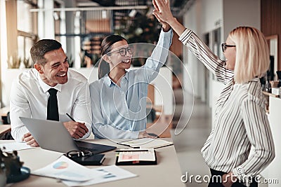 Laughing businesswomen high fiving together during an office mee Stock Photo