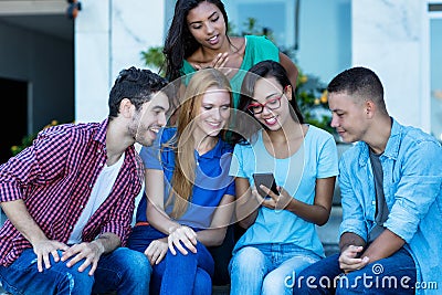 Laughing female influencer with mobile phone and group of young adult friends Stock Photo