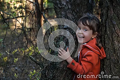 Laughing five-years-old girl stands between two trees in autumn forest. Stock Photo