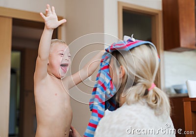 A laughing handicapped down syndrome boy with his mother indoors having fun. Stock Photo