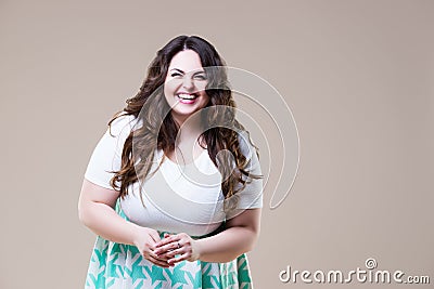 Laughing happy plus size model in casual clothes, fat woman on beige background Stock Photo