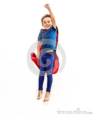 Laughing isolated superhero child jumping high, flying with arm raised Stock Photo