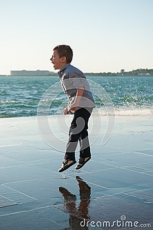 Laughing jumping little boy in the background of a sea storm Stock Photo