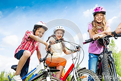 Laughing kids in helmets hold bike handle-bars Stock Photo