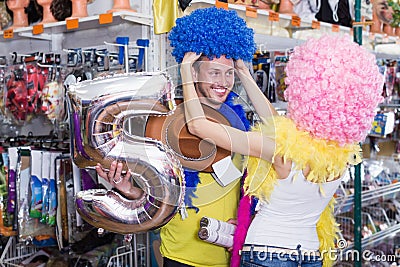 Laughing male with girlfriend trying clown wigs Stock Photo