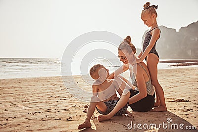 Laughing Mother and children sitting on a sandy beach Stock Photo