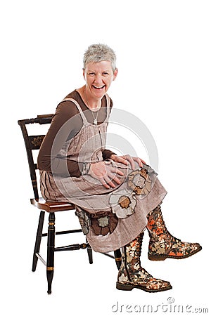 Laughing older woman sits and leans forward Stock Photo