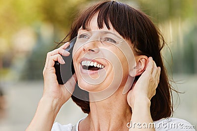 Laughing older woman talking on smart phone outside Stock Photo