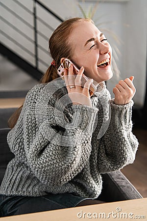 Laughing redhead sitting on the couch having a conversation on the phone at home Stock Photo