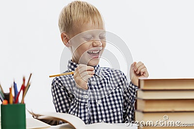 A laughing schoolboy sits at a table with textbooks and does homework. Back to school. White background Stock Photo