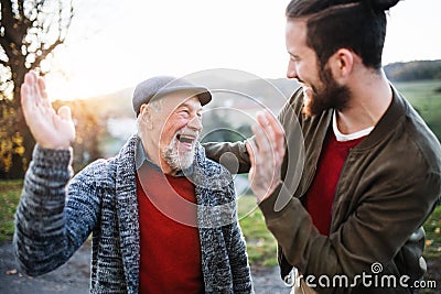 Laughing senior father and his son on walk in nature, giving high five. Stock Photo