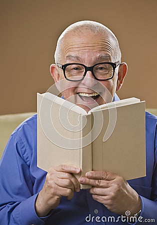 Laughing senior male reading a book Stock Photo